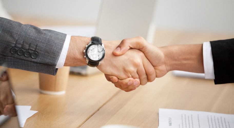 Close up view of handshake, two businessmen in suits shaking hands as concept of trust, good partnership deal, signing contract agreement at meeting, gratitude for help support in business